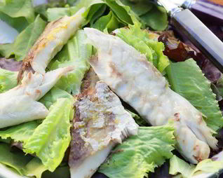 Копченая рыба на листьях салата